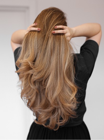Delikatna stylizacja długich blond włosów z naturalnym wykończeniem i miękkim układem pasm