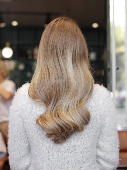 Gładka fryzura na średnich blond włosach z lekką objętością i naturalnym efektem