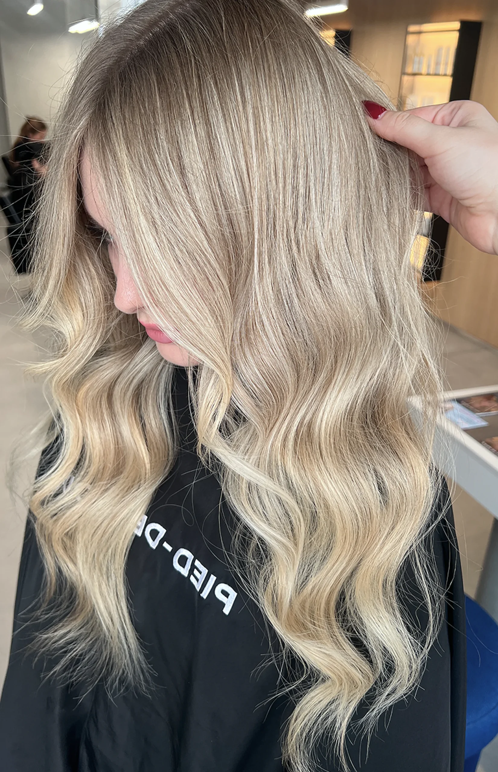 Tył głowy kobiety o długich, pofalowanych włosach blond.